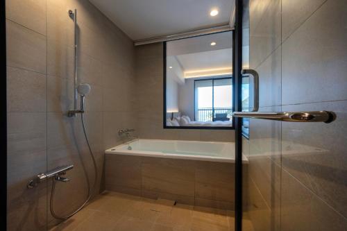 a bathroom with a tub and a shower with a window at seven x seven Itoshima in Itoshima