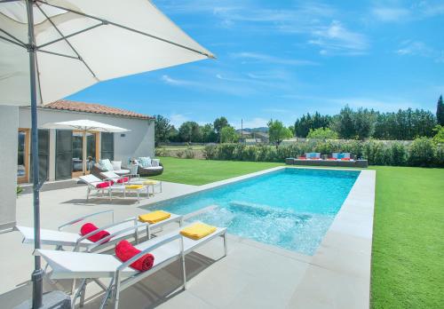um quintal com uma piscina com cadeiras e um guarda-sol em Owl Booking Villa Mir - Luxury Retreat em Pollença