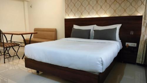 a bedroom with a large bed with a table and a chair at Hotel Sai Nidhi Executive-MindSpace Airoli Navi Mumbai in Navi Mumbai