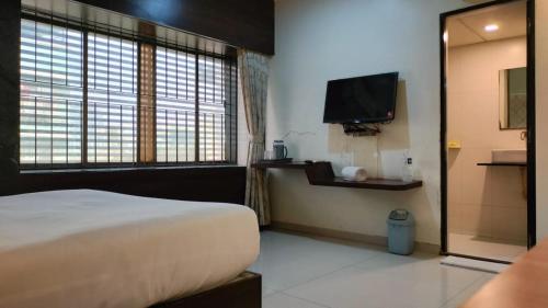 a bedroom with a bed and a flat screen tv at Hotel Sai Nidhi Executive-MindSpace Airoli Navi Mumbai in Navi Mumbai