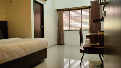a bedroom with a bed and a table and a window at Hotel Sai Nidhi Executive-MindSpace Airoli Navi Mumbai in Navi Mumbai