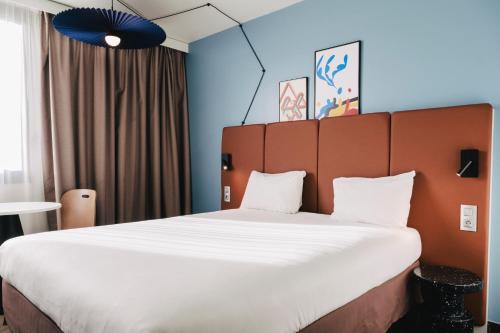 uma grande cama num quarto com uma grande cama branca em Ibis Rouen Centre Rive Gauche Mermoz em Rouen