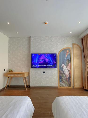 a bedroom with two beds and a tv on the wall at Mia Apec Mandala Phú Yên in Tuy Hoa