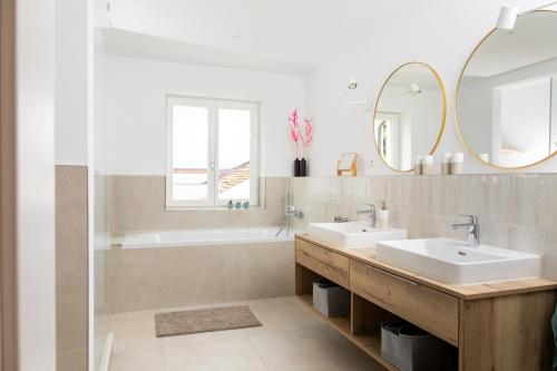 een badkamer met 2 wastafels, een bad en een spiegel bij Ferienhaus Luv und Meer in Warnemünde