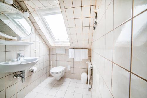 a bathroom with a sink toilet and a window at Pension Wosmaaren in Norddorf