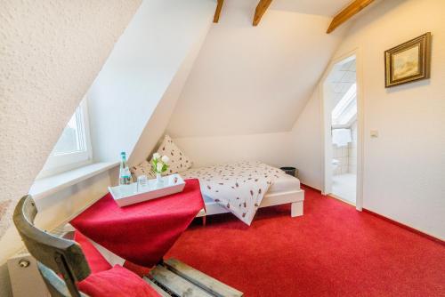 a attic room with a bed and a red carpet at Pension Wosmaaren in Norddorf