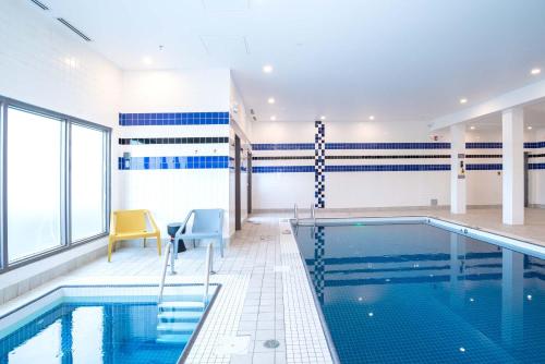 a swimming pool with two chairs and a yellow chair next to it at Sandman Hotel Calgary Airport in Calgary