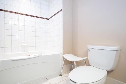 a white bathroom with a toilet and a tub at Sandman Hotel Calgary Airport in Calgary