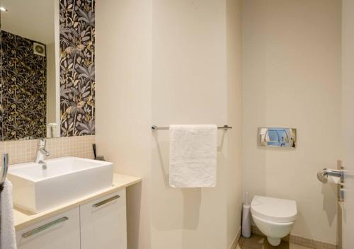 La salle de bains blanche est pourvue d'un lavabo et de toilettes. dans l'établissement Plett Holiday Apartment, à Plettenberg Bay