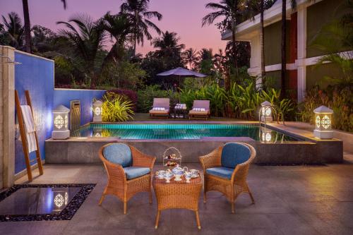 a patio with a table and chairs next to a pool at Taj Exotica Resort & Spa, Goa in Benaulim