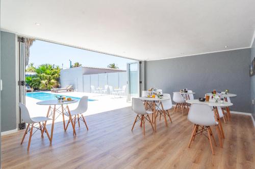 una sala da pranzo con tavoli, sedie e piscina di Bloubergstrandlodge a Bloubergstrand