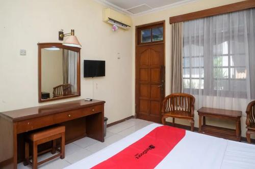 a bedroom with a bed and a dresser and a mirror at RedDoorz Plus @ Laweyan in Solo