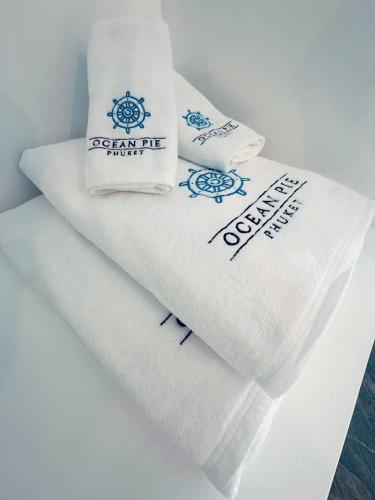 a pile of towels with logos on them at Ocean Pie Phuket - Adult Only in Rawai Beach