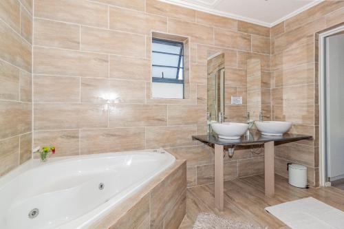 a bathroom with two sinks and a tub at Bloubergstrandlodge in Bloubergstrand