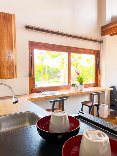 a kitchen with a sink and a kitchen counter with a window at Sithaya Garden House @14 in Ban Thung Luang (1)