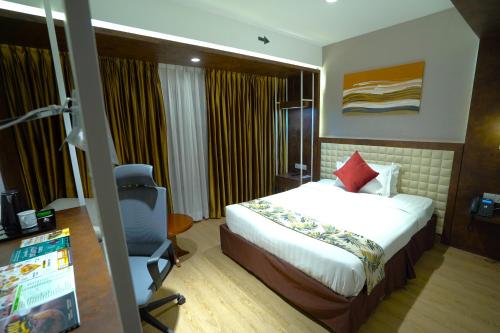a bedroom with a bed and a desk and a chair at Grand River View Hotel - Rajshahi in Rājshāhi