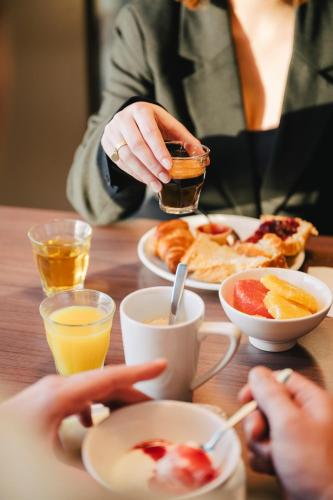 a woman is sitting at a table with breakfast food at Ibis Rouen Centre Rive Gauche Mermoz in Rouen