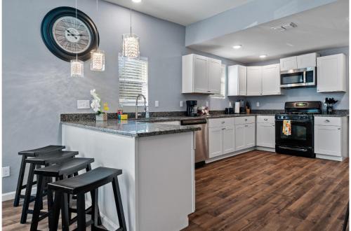 a kitchen with white cabinets and a counter with stools at Step into Comfort in this 3BR2BA Downtown Retreat in San Antonio