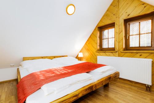 a bed in a room with wooden walls and windows at Hotel Leyla in Frymburk