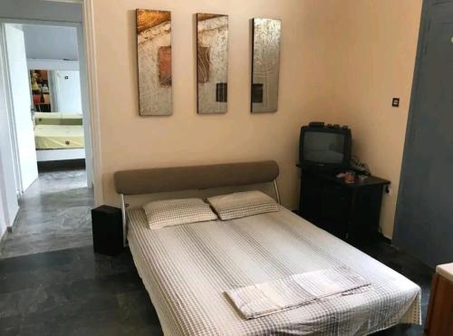 a bedroom with a bed with three paintings on the wall at Nest next to the center in Mytilene