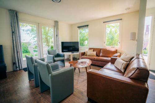 a living room with leather furniture and a tv at B&B de Luwte Cottage in Zwolle