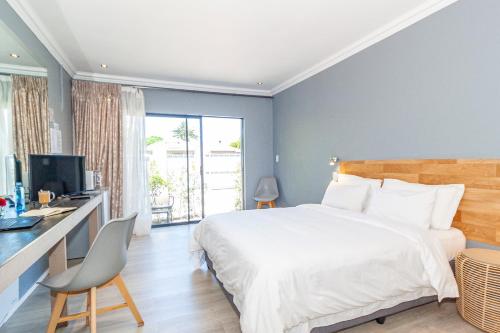 a bedroom with a bed and a desk with a computer at Bloubergstrandlodge in Bloubergstrand
