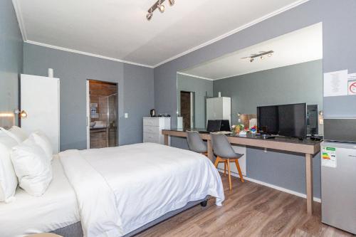 a bedroom with a bed and a desk with a computer at Bloubergstrandlodge in Bloubergstrand