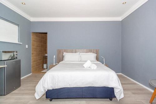 a bedroom with a large bed with blue walls at Bloubergstrandlodge in Bloubergstrand