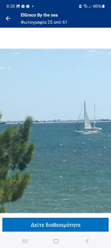 a sailboat on the water with a boat in the ocean at Maria Apartments in Néa Karváli