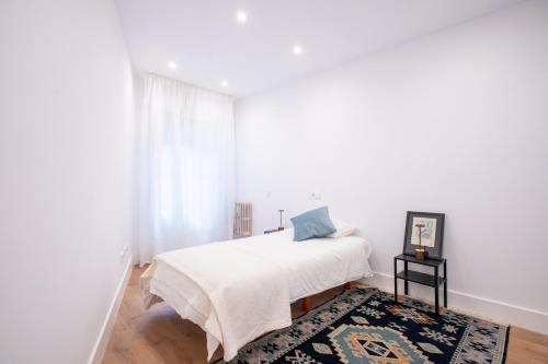 a white bedroom with a bed and a rug at Llorenzu El Santu - Vistas al Mar · 4hab · 3 baños in Gijón