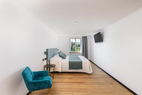 um quarto com uma cama e uma cadeira azul em Hotel Rheingerbe em Stein am Rhein