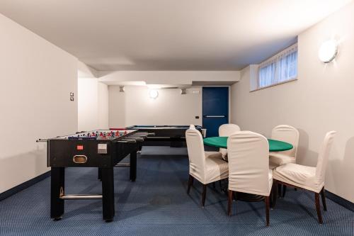 una stanza con tavolo da ping pong e sedie di Hotel garni Meledrio a Dimaro