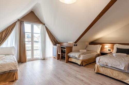 a attic bedroom with two beds and a desk at Hotel garni Meledrio in Dimaro