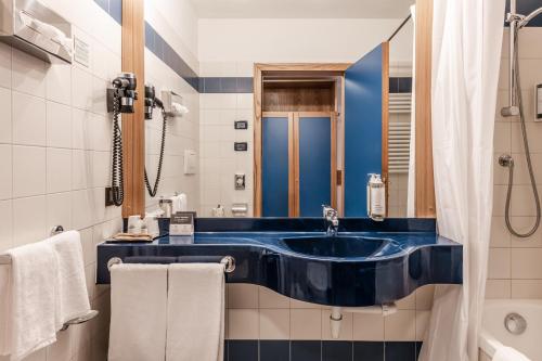 a bathroom with a blue sink and a shower at Hotel garni Meledrio in Dimaro