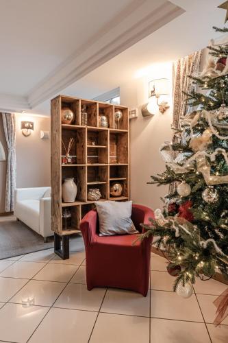 a christmas tree in a living room with a red chair at Hotel garni Meledrio in Dimaro