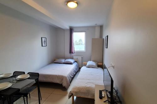 een kamer met 2 bedden en een tafel en stoelen bij Mon petit coin de paradis in Montfermeil