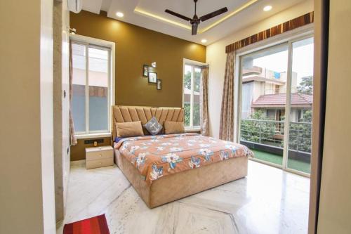 a bedroom with a large bed and large windows at IN 4BHK VILLA LONAVALA in Lonavala