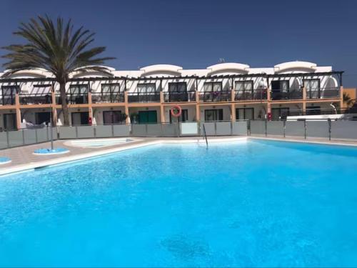 a large swimming pool in front of a building at Apartamento Happyness Complex Amaya Fuerteventura in Costa de Antigua
