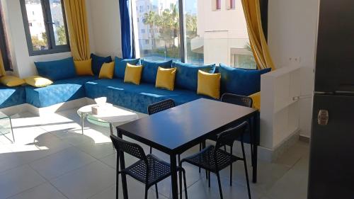 uma sala de estar com um sofá azul e uma mesa e cadeiras em Duplex Deluxe Arous Al Bahr em Tânger