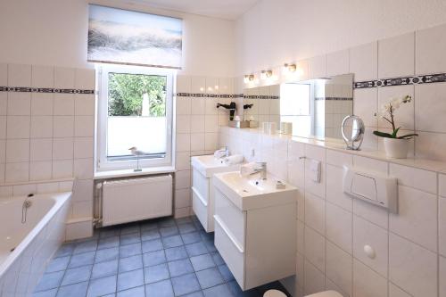 a white bathroom with a sink and a bath tub at Haus der kurzen Wege in Warnemünde
