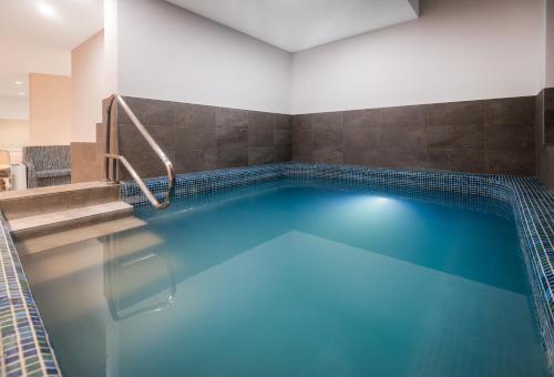 a swimming pool with blue water in a building at Hunguest Bük - ex Répce és Répce Gold in Bük