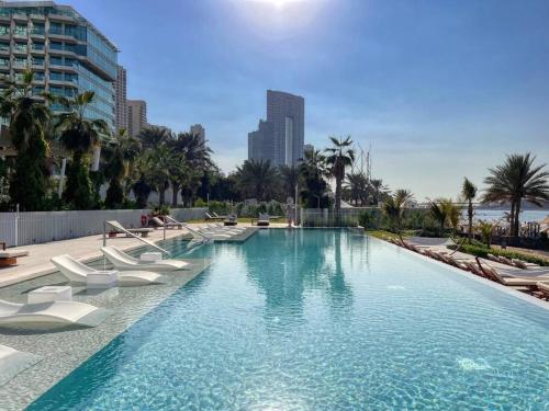 een groot zwembad met witte ligstoelen in een stad bij Stunning 2BR with Sea and Ain Dubai View at JBR in Dubai