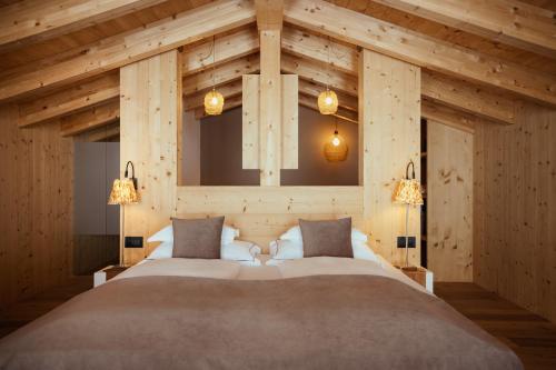 a bedroom with a large bed in a room with wooden walls at Villa Flora Mountain Lodges in San Cassiano