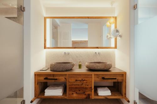 a bathroom with two sinks and a mirror at Villa Flora Mountain Lodges in San Cassiano