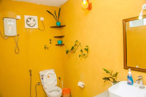 bagno giallo con servizi igienici e lavandino di Feeling tip'sea rooftop villa a Mirissa