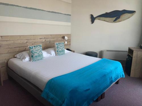 a bedroom with a bed with a whale picture on the wall at Baya Hotel in Capbreton