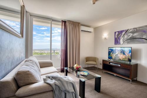 uma sala de estar com um sofá e uma televisão de ecrã plano em Park Regis Concierge Apartments em Sydney