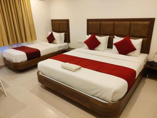 2 camas en una habitación de hotel con almohadas rojas en Relax Inn, en Bangalore