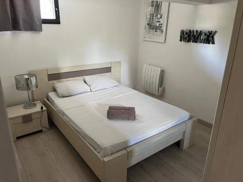 - une chambre dotée d'un lit blanc avec une boîte marron dans l'établissement la brigantine 2, à La Ciotat