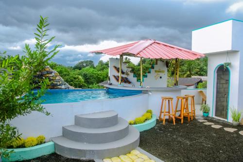 a resort with a swimming pool and a bar with stools at Feeling tip'sea rooftop villa in Mirissa